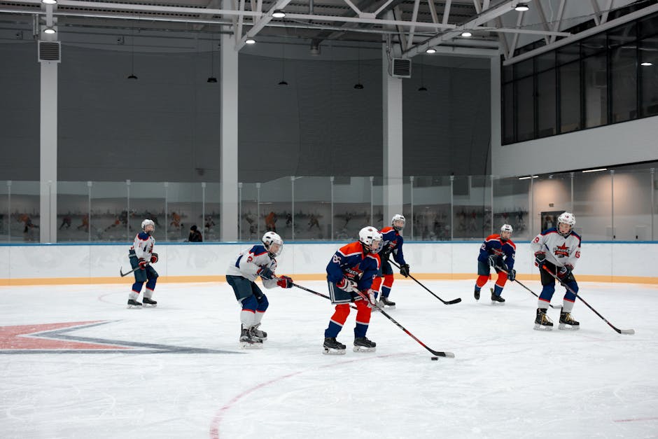 A group of athletes playing ice hockey indoors, showcasing teamwork and skills.