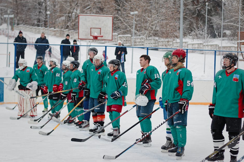 Group of male ice hockey players standing in a row during a winter match outdoors.
