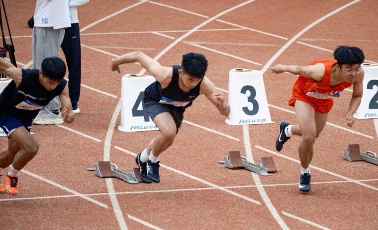 Young male sprinters launching off at the starting line, showcasing athletic determination on the track.