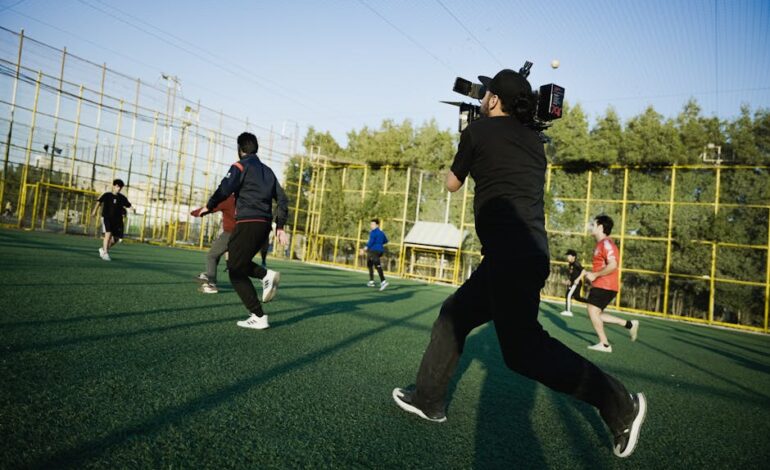 A dynamic scene of a camera crew capturing an intense soccer match on a sunny day.