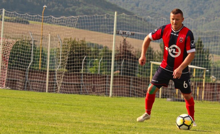 A soccer player in action on a sunny day at a field in Rajec, Slovakia.