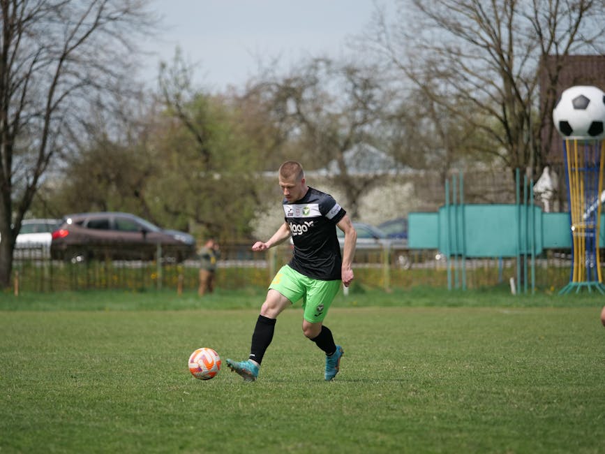 Focused young soccer player practicing on a vibrant green field outdoors.