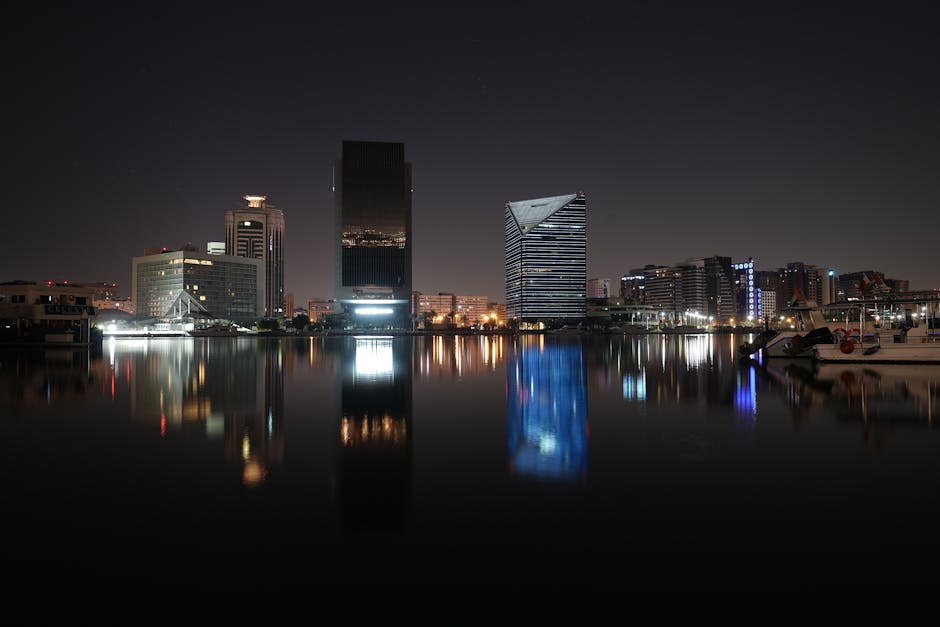 Capture of Dubai skyline at night with reflections in water, showcasing modern architecture.