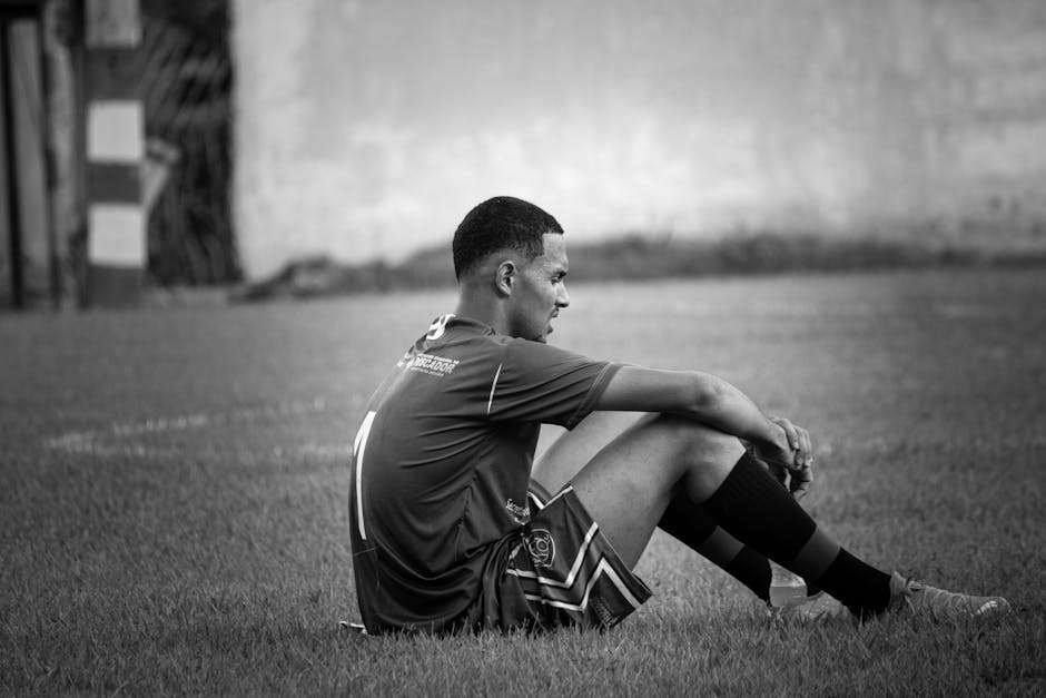 Black and white photo of a soccer player resting on the field, Pescador, Brazil.