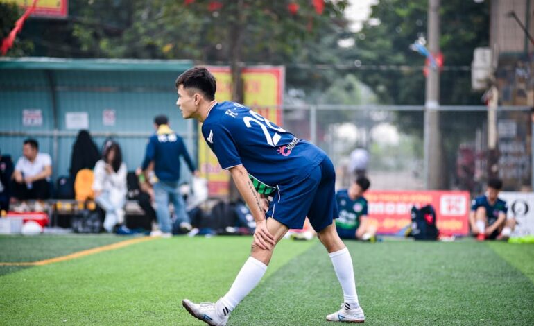 Soccer player stretching on a football field in Hanoi, Vietnam, preparing for a game.
