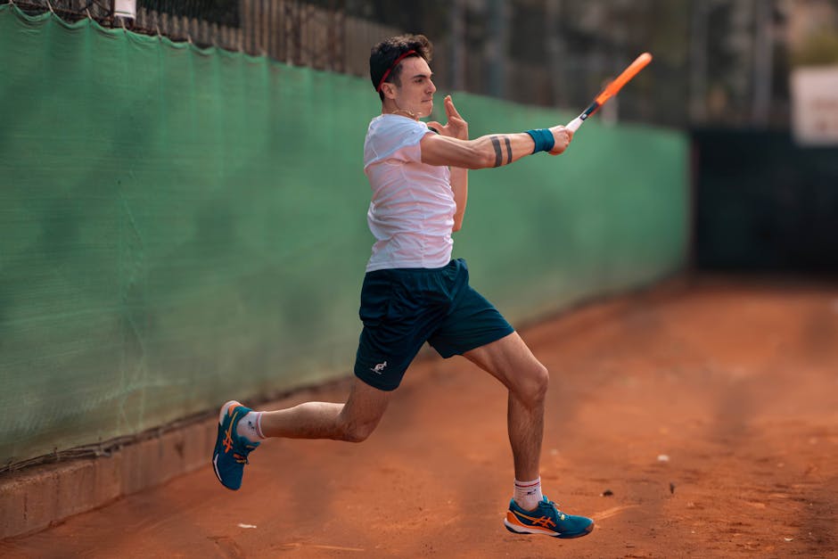 A focused tennis player mid-swing on a clay court, showcasing energy and sportsmanship.