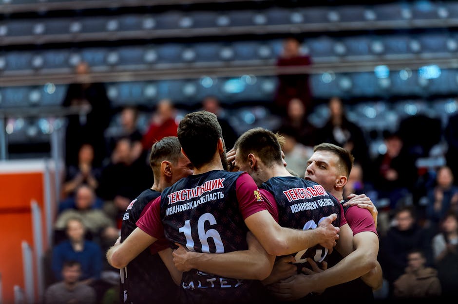 Volleyball players embrace in celebration during an indoor game.