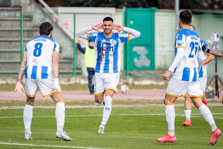 Excited soccer players celebrating a goal on an outdoor field during a match.