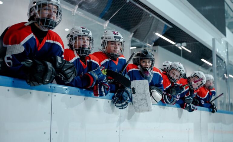 A junior ice hockey team waits eagerly at the rink edge, embodying teamwork and anticipation.