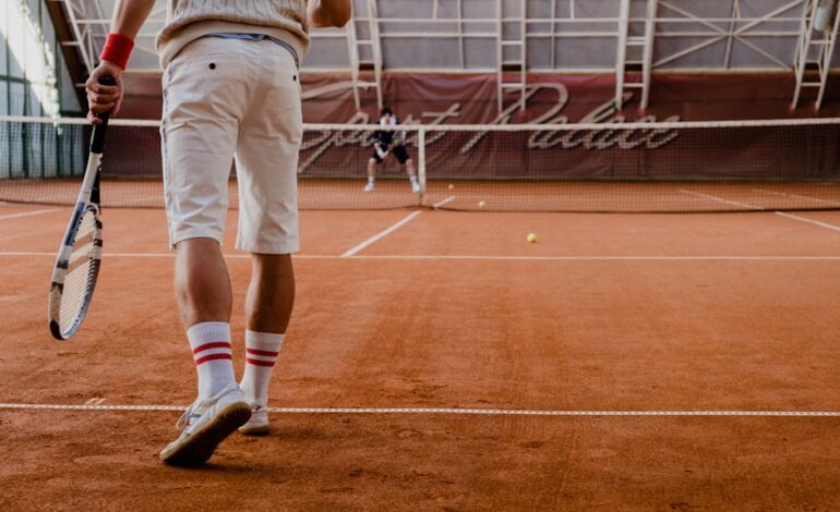 Players competing in a tennis match on an indoor clay court.