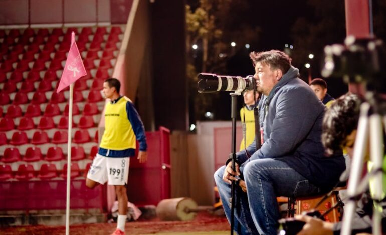 Soccer coach intensely watches game at night stadium, focused on strategy.