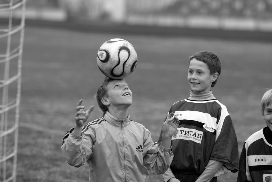 Young soccer players having fun practicing ball balancing on their heads outdoors.