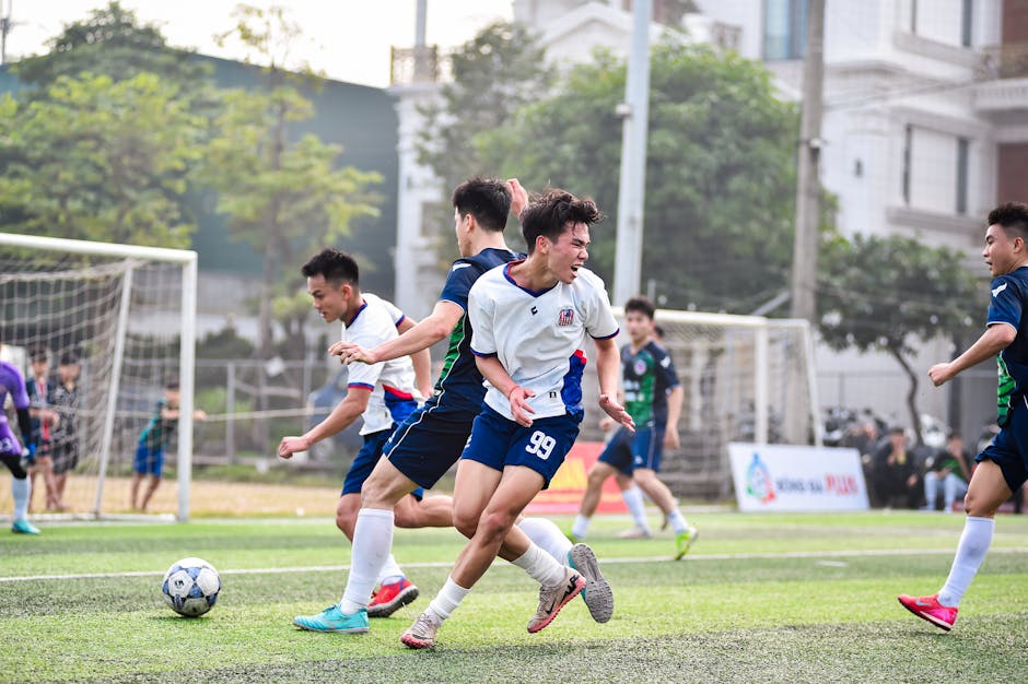 Football players in action during a vibrant match on a sunny day in Hanoi, Vietnam.