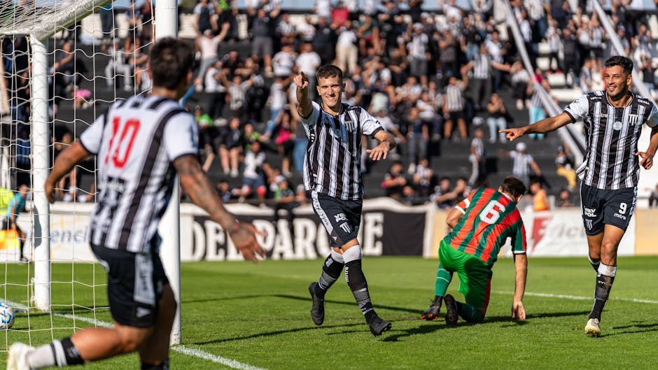 Soccer players in black and white jerseys celebrating a goal during a match.