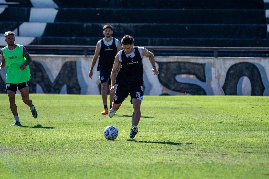 Four soccer players practicing on an outdoor field during the day. Focus on active sports training.