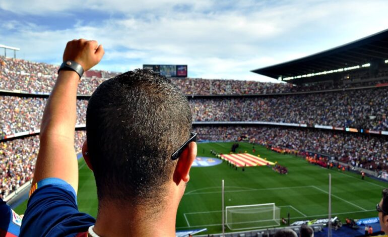 A passionate football fan cheers among a crowd at a bustling stadium, creating an electrifying atmosphere.