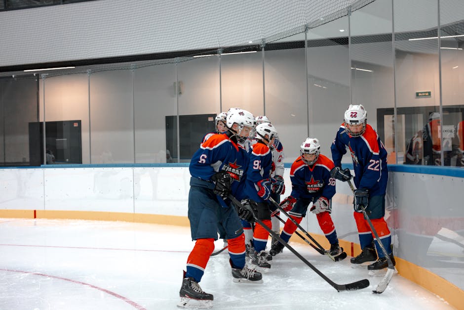 Group of young ice hockey players strategizing during a game on an indoor ice rink.