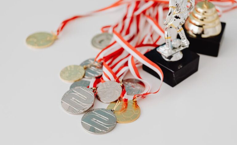 A varied collection of silver and gold medals alongside trophies on a white surface, showcasing achievement.