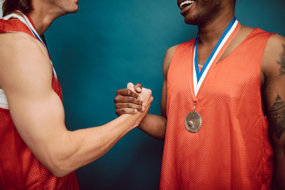 Two basketball players in red jerseys celebrating with a handshake and medals.
