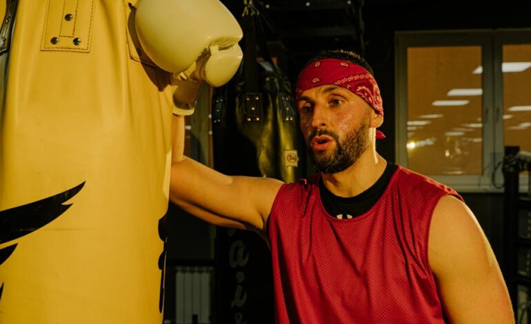 A boxer takes a break while training with a punching bag in a gym.