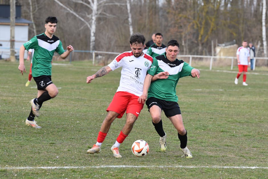 Two soccer players competing for the ball during a match outdoors on a grass field.
