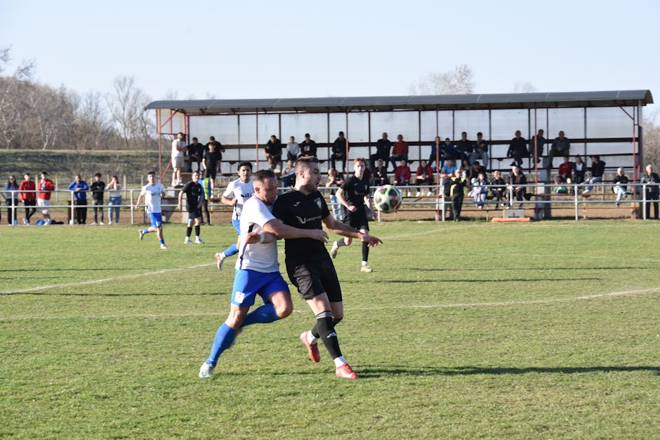Soccer players in action on a sunny day in Vásárosnamény, Hungary with spectators watching.