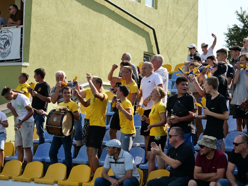 Enthusiastic crowd of sports fans cheering at a daytime outdoor match.