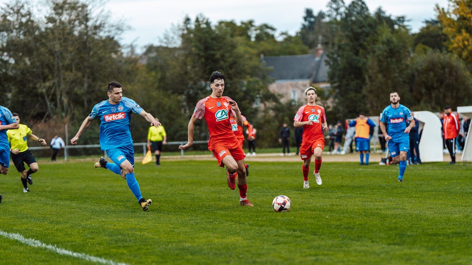 Dynamic football match action captured in France with players in red and blue jerseys.