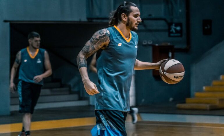 Athletes focused on basketball training indoors, emphasizing teamwork and skills.