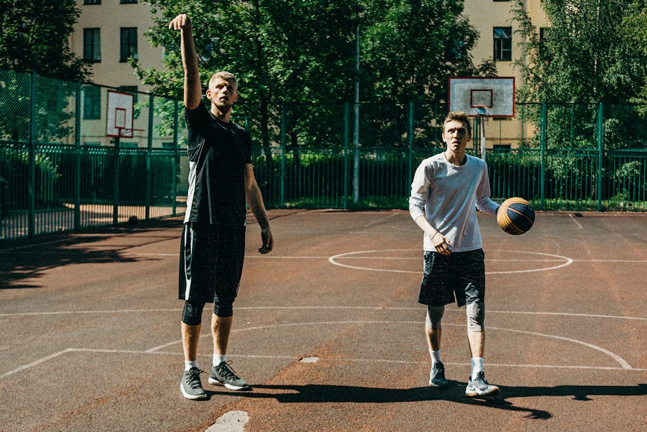 Two men enjoying a game of basketball on an outdoor court, showcasing teamwork and sportsmanship.