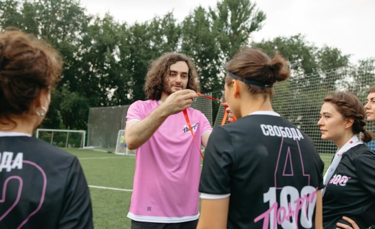 Women's soccer team receiving medals from coach on the field. Celebratory moments captured.