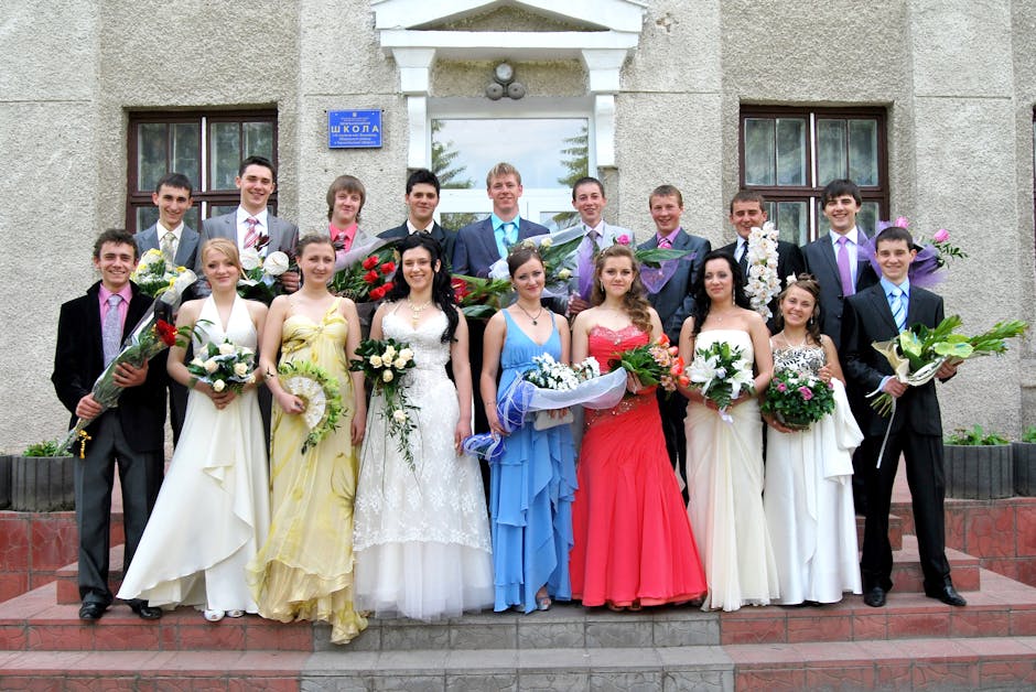 A group of young adults in formal attire posing with bouquets at a graduation ceremony.