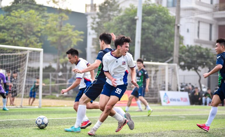 Football players in action during a vibrant match on a sunny day in Hanoi, Vietnam.