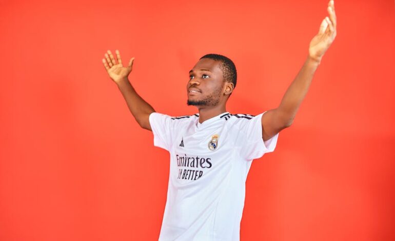 An enthusiastic football fan celebrating with arms raised in a jersey against a red background.