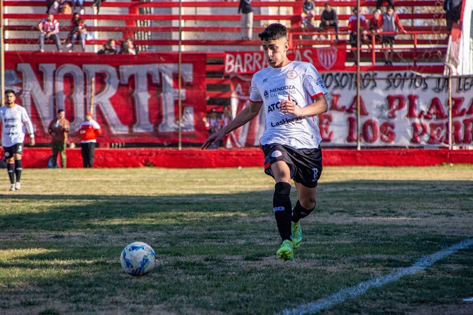 A focused soccer player dribbling the ball towards the goal during a match.