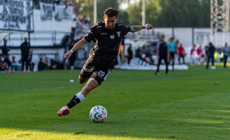 Dynamic action shot of a footballer kicking the ball on the field during a match.