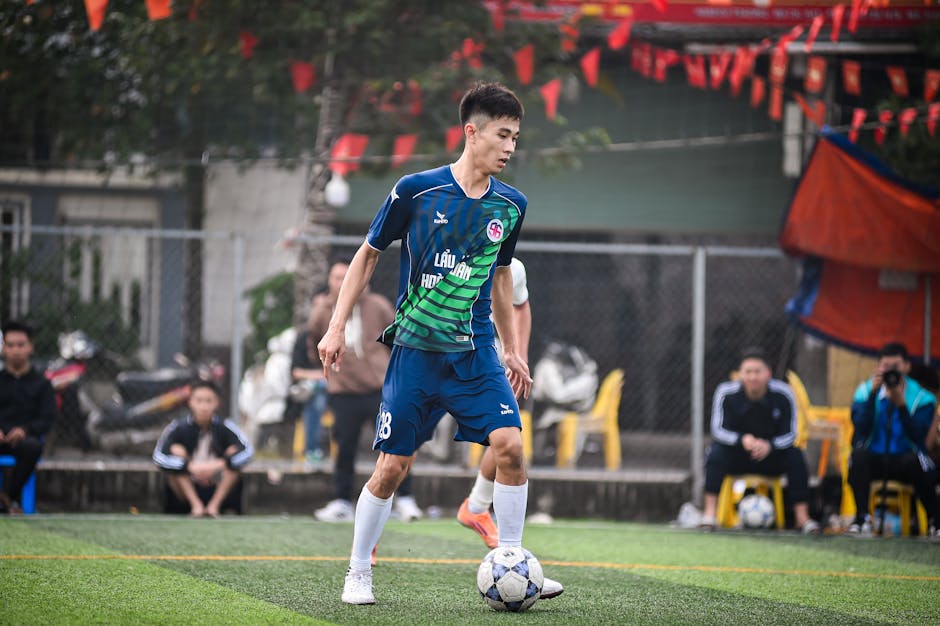 A young male football player dribbling during a match in Hanoi, Vietnam.