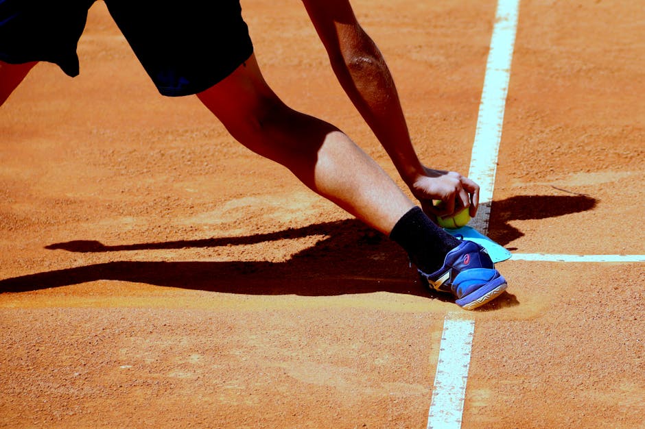 A tennis player reaching for a ball on a sunny clay court in Goiânia, Brazil.