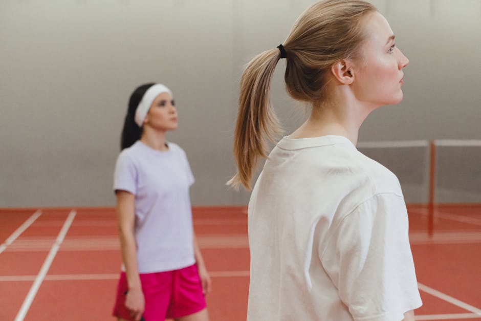 Two women engaged in a badminton match on an indoor court, highlighting active sportswear.