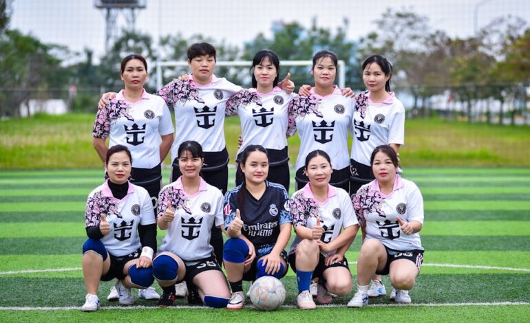 Group of women football players posing on a field in Hanoi, Vietnam, showcasing team spirit.
