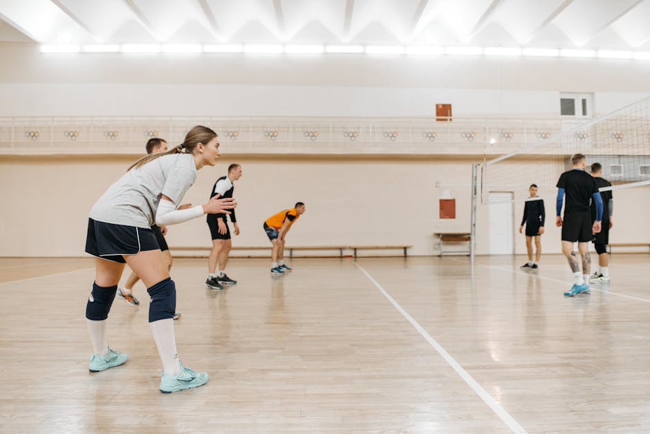 Athletes playing an intense volleyball match indoors, showcasing teamwork and sportsmanship.