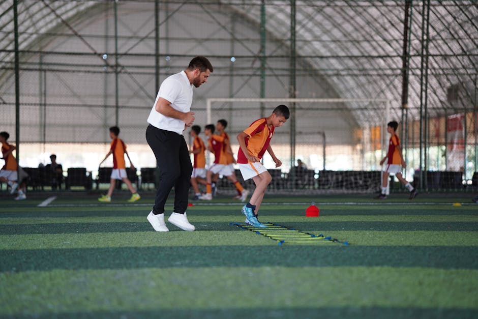 A young boy trains under a coach in a structured soccer practice indoors.