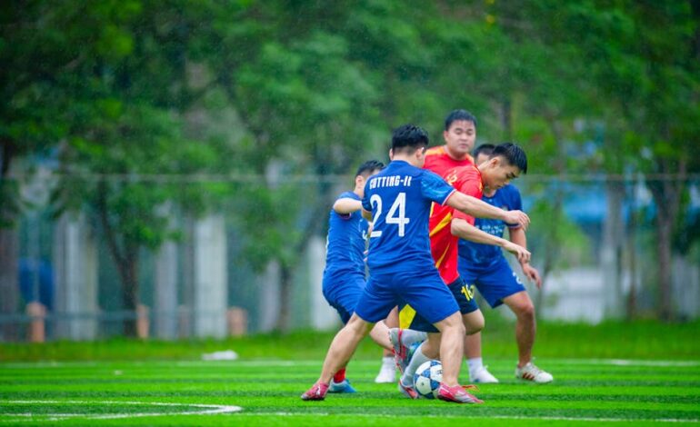 Exciting action during an amateur football match in Hanoi, Vietnam, captured on a rainy day.