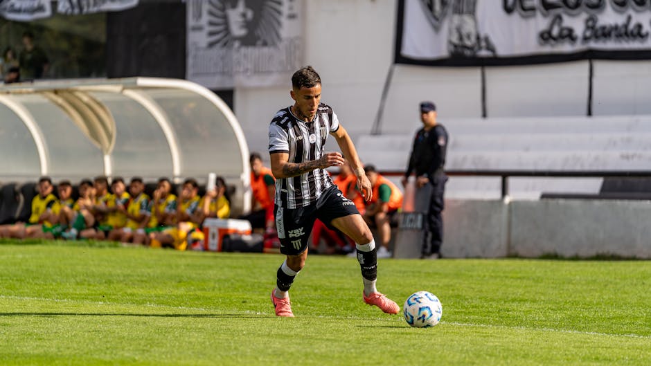 Soccer player in striped uniform dribbles the ball on the field.
