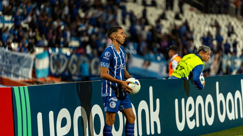 Football player in blue jersey readies for throw-in during live match.