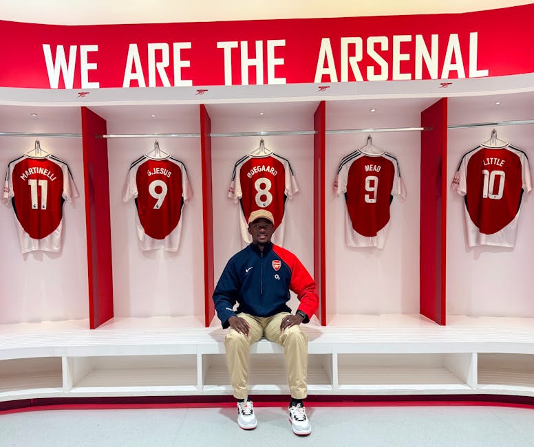 Visitor in Arsenal locker room with team jerseys and club branding.