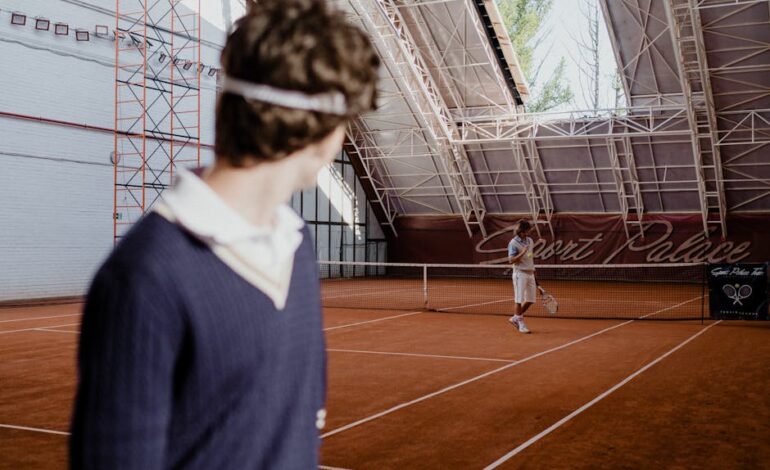Tennis players on an indoor clay court during a competitive match.