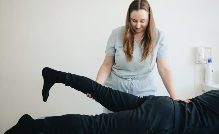 A physiotherapist helps a patient stretch their leg during a therapy session in Vilnius clinic.