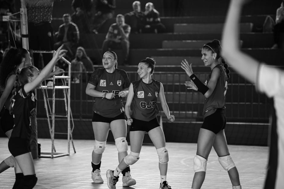 Black and white photo of a female volleyball team celebrating after a successful game.