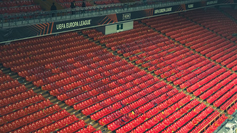 Empty red stadium seats at UEFA Europa League venue, providing spacious copyspace.